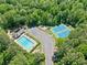 Aerial view of a community pool, tennis courts, and playground surrounded by lush greenery at 614 Springharbor Dr, Woodstock, GA 30188