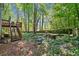 Backyard with a wooden deck and staircase, featuring lush greenery and tall trees at 614 Springharbor Dr, Woodstock, GA 30188