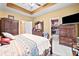Comfortable main bedroom with tray ceiling, wood furniture, and ensuite bath access at 614 Springharbor Dr, Woodstock, GA 30188