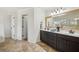 Bright bathroom with double vanity, dark wood cabinets, and decorative mirror and fixtures at 7115 Doncaster Ct, Cumming, GA 30040