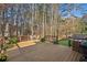 Spacious wooden deck featuring a grill, dining set, potted plants and mature trees at 7115 Doncaster Ct, Cumming, GA 30040