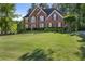 Beautiful two-story brick home with manicured lawn and mature trees providing shade and curb appeal at 7115 Doncaster Ct, Cumming, GA 30040