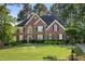 Traditional brick home with well-manicured lawn, lush landscaping, and a welcoming front entrance at 7115 Doncaster Ct, Cumming, GA 30040