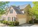 Side exterior featuring a two-car attached garage, basketball hoop, and well-maintained landscaping at 1010 Forest Creek Dr, Canton, GA 30115