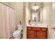 Cozy bathroom with cherry vanity, white sink, shower with printed curtain, and earth-toned flooring at 3448 Clear Stream Ne Run, Auburn, GA 30011