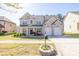 Inviting two-story brick home with a well-kept lawn, colorful flowers, and an attached two-car garage at 3448 Clear Stream Ne Run, Auburn, GA 30011