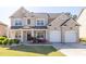 Charming two-story brick home featuring a manicured lawn, flower beds, and a two-car garage at 3448 Clear Stream Ne Run, Auburn, GA 30011