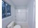 Bright bathroom features a tub with shower, window, and modern white fixtures at 2637 Sol Ct, Ellenwood, GA 30294