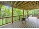 This property includes a composite, covered deck with black metal railings and outdoor seating surrounded by mature trees at 5276 Weatherwood Trce, Marietta, GA 30068