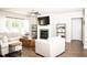 Cozy living room with a fireplace, white sofas, and large windows offering natural light at 6340 Arlington Cir, Cumming, GA 30041
