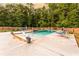 Outdoor pool area featuring lounge chairs, and a stone surround in a wooded backyard at 632 Creekside Trce, Covington, GA 30014