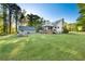 Expansive backyard with lush green lawn, mature trees, a fire pit, a large shed, and a covered back porch at 576 Tope Rd, Sharpsburg, GA 30277
