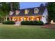 Exterior shot of home with a sprawling front lawn, covered porch, manicured hedges, and dormer windows at 576 Tope Rd, Sharpsburg, GA 30277
