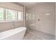 Bright bathroom showcases a modern soaking tub beside a glass-enclosed shower with white tiling and wood look floors at 2675 Sugar Mill Dr, Atlanta, GA 30316