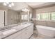 Bright bathroom featuring a soaking tub, granite counters, double sinks, and a glass-enclosed shower with natural light at 2675 Sugar Mill Dr, Atlanta, GA 30316