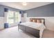 Bedroom with accent blue wallpaper, complemented by white wainscoting, a large bed, and natural light from the windows at 2675 Sugar Mill Dr, Atlanta, GA 30316