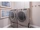 Laundry room featuring modern gray front load washer and dryer with dark neutral colored walls and decor at 2675 Sugar Mill Dr, Atlanta, GA 30316