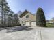 Spacious three-car garage with an extra tall evergreen tree next to the expansive driveway and fenced in lawn at 1594 Stoddard Nw Ct, Kennesaw, GA 30152