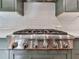 Close up of a modern gas range with stainless steel appliances and white backsplash at 1594 Stoddard Nw Ct, Kennesaw, GA 30152