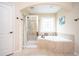 Bright bathroom featuring a large soaking tub, a separate glass-enclosed shower, and a decorative window at 455 Cooper Woods Se Ct, Smyrna, GA 30082