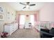 Charming Bedroom with pink accents, featuring a ceiling fan, crib, dresser, and comfortable seating at 455 Cooper Woods Se Ct, Smyrna, GA 30082