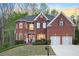 Charming red brick home featuring a two-car garage and manicured front yard, at dusk at 455 Cooper Woods Se Ct, Smyrna, GA 30082