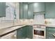 Galley kitchen with green cabinetry, stainless steel appliances, and white tile backsplash at 1216 Beech Valley Ne Rd, Atlanta, GA 30306