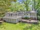 Backyard of a light gray home with a large deck and mature trees at 3150 Rilman Nw Rd, Atlanta, GA 30327