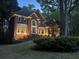 Elegant brick home at dusk, showcasing landscape lighting, mature trees, and manicured lawn at 120 Stanmore Ct, Roswell, GA 30075