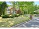 Brick home with lush landscaping and mature trees, complemented by a long driveway and manicured lawn at 120 Stanmore Ct, Roswell, GA 30075