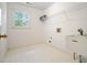 Neat laundry room with white tiled floor, sink, storage, window, and metallic shelf at 120 Stanmore Ct, Roswell, GA 30075