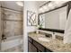 Well-lit bathroom with a granite countertop, dark wood cabinets, decorative mirror, and a tub and shower combination at 239 Devonwood Dr, Atlanta, GA 30328