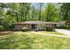 Charming single-story home with stone accents, a well-manicured lawn, and mature trees creating a private setting at 239 Devonwood Dr, Atlanta, GA 30328