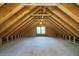 Spacious unfinished attic with exposed wooden beams, plywood flooring, and a centered window at 2921 Huntcliff Dr, Marietta, GA 30066