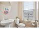 Half bath featuring a pedestal sink, toilet, decorative mirror, and natural light at 3229 Hallmark Ln, Buford, GA 30519