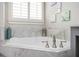 Close up of a soaking tub with marble surround and modern fixtures at 520 Tackett Farms Rd, Smyrna, GA 30082
