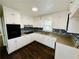 Bright kitchen featuring white cabinets, stainless steel appliances, and dark wood-look flooring at 1277 4Th Ave, Auburn, GA 30011