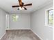 This bedroom features neutral walls, carpet, a ceiling fan, and windows that allow for natural light at 190 Sunrise Cir, Riverdale, GA 30274