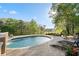Relaxing backyard showcasing a sleek pool with a stone accent wall and lounge chairs, surrounded by lush greenery at 177 Grandmar Chase, Canton, GA 30115