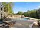 Backyard featuring a large pool, stone retaining wall, patio with lounge chairs, and lush green trees at 177 Grandmar Chase, Canton, GA 30115