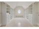 Spacious walk-in closet with custom shelving and drawers, illuminated by a round window at 5694 Brendlynn Dr, Suwanee, GA 30024