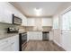 Modern kitchen with white cabinets, stainless steel appliances, granite countertops, and wood-look flooring at 2041 W Flat Shoals Ter, Decatur, GA 30034