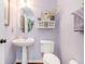 Half bath with a pedestal sink, an oval mirror with vanity light, and lavender colored walls at 624 Spanish Oak Dr, Acworth, GA 30102