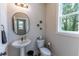A cozy half-bathroom with a pedestal sink, toilet, and a window letting in natural light at 842 Bridgewater Sw St, Atlanta, GA 30310