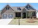 Charming home with a well-manicured lawn, gray brick, stone accents, and a modern garage door at 2925 Coach River Way, Cumming, GA 30040