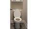 The toilet is white and features a closed front, and is set against neutral walls and grey tile flooring at 2925 Coach River Way, Cumming, GA 30040