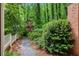 View of backyard landscaping featuring a brick retaining wall, pea gravel pathway, and mature trees and bushes at 297 Breeze Hill Ln, Canton, GA 30114