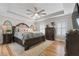 Spacious main bedroom featuring a tray ceiling, a ceiling fan, hardwood floors, and a large comfortable bed at 125 Abner Dr, Mcdonough, GA 30252