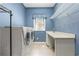 Bright laundry room with three white front-loading machines, a sink, and ample counter space at 2220 Peachtree Rd, Cumming, GA 30041