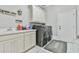 Laundry room features white cabinets, utility sink, washer, and dryer with tile flooring at 3233 Bagley Psge, Duluth, GA 30097